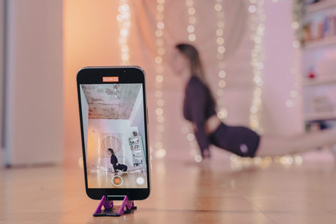 A girl taking a video of her yoga session with an iPhone on the Pocket Tripod