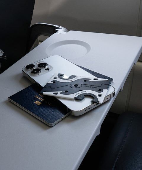 A folded Pocket Tripod, an iPhone, and a passport on an airplane tray