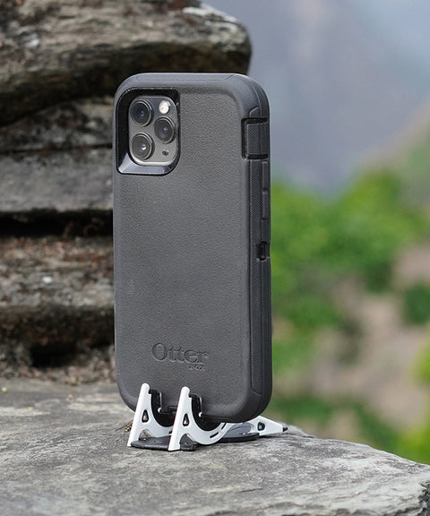 An iPhone in a thick Otterbox case on a Pocket Tripod on a flat rocky surface