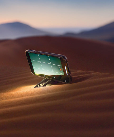 An iPhone on a Pocket Tripod in horizontal orientation on a sand dune in the desert capturing a time-lapse video.