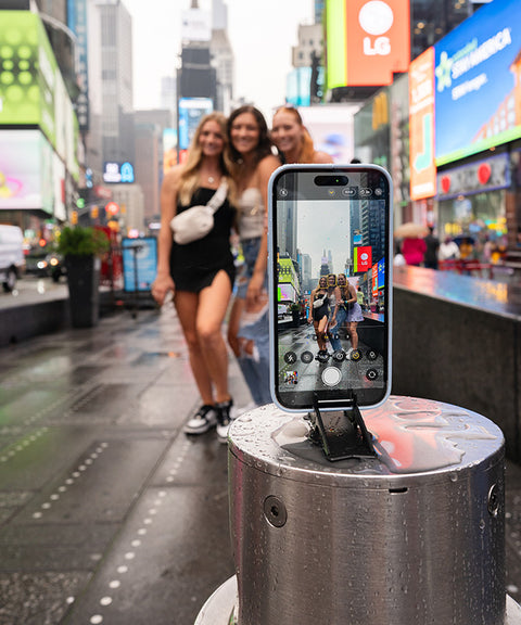 A group of girls using their iPhone on a Pocket Tripod in Times Square New York to take a group picture