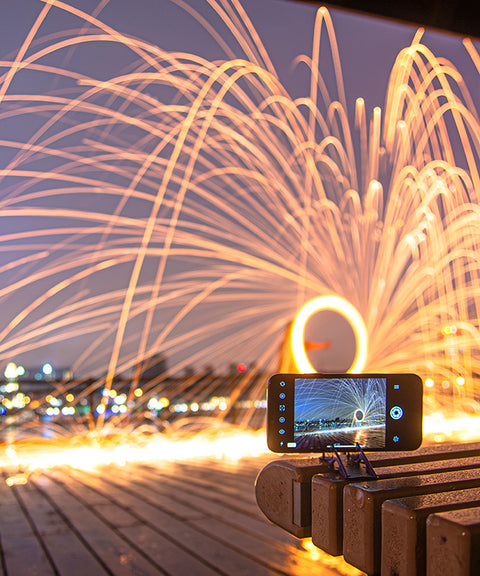 A phone in horizontal orientation being used with long exposure to capture a fire splint light painting 