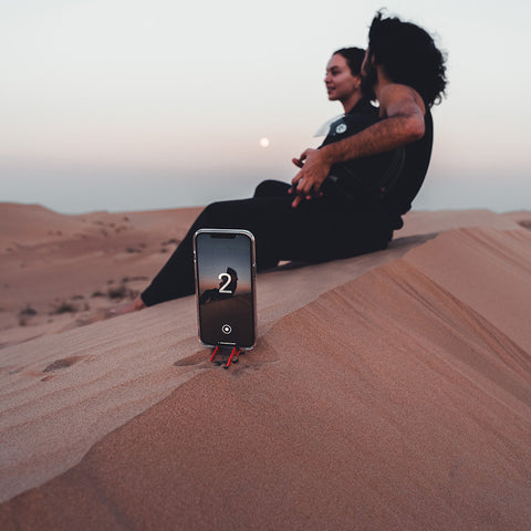 A couple using their iPhone on a Pocket Tripod to take a picture in the dessert